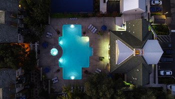 Nightime Drone of Pool Area with Lounge Chairs, Trees and Plants